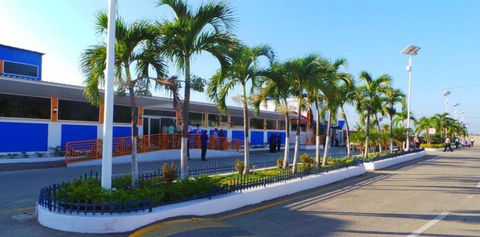 Façade colorée de l'Aéroport International Hugo Chávez du Cap-Haïtien avec palmiers et aménagement moderne