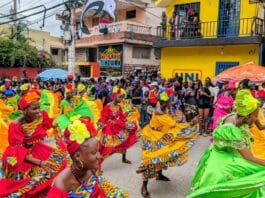 Carnaval de Jacmel 2026 : Tradition, Art et Défis Économiques Groupe de danse haïtien défilant et dansant sur l'avenue Baranquilla lors du défilé du Carnaval de Jacmel 2026 dans le Sud-Est d'Haïti.