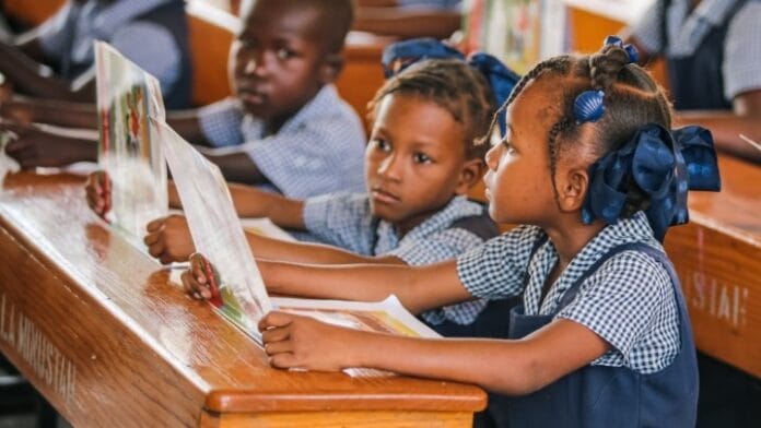 Des élèves attentifs tenant un livre dans une classe représentant les défis de l'éducation en Haïti.